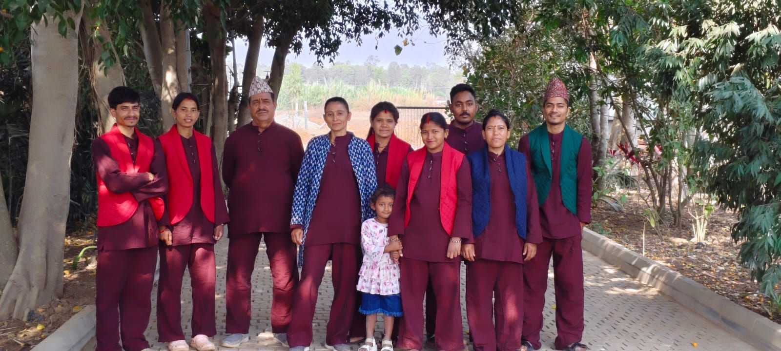 The Orchid Tree team at the estate near Bangalore, in maroon and red, among the trees
