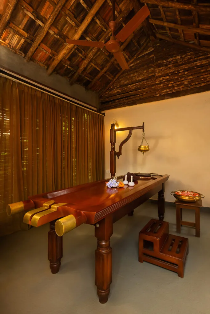 Ayurvedic wellness room with traditional wooden massage table at Orchid Tree Wellness Retreat.