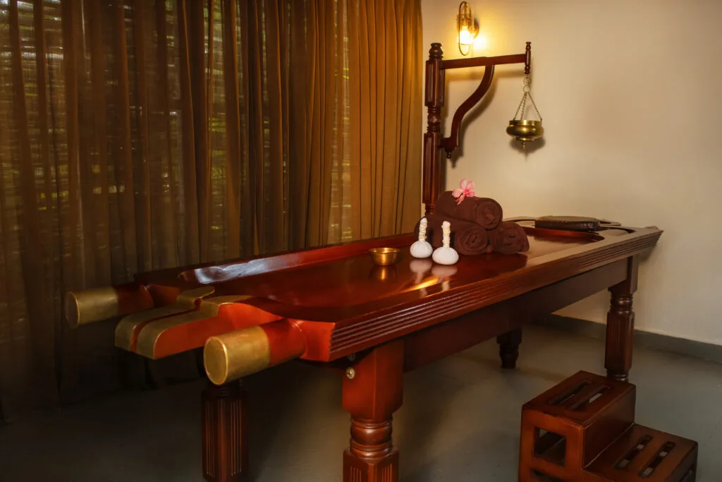 Ayurvedic therapy room with traditional wooden massage table at Orchid Tree Wellness Retreat.