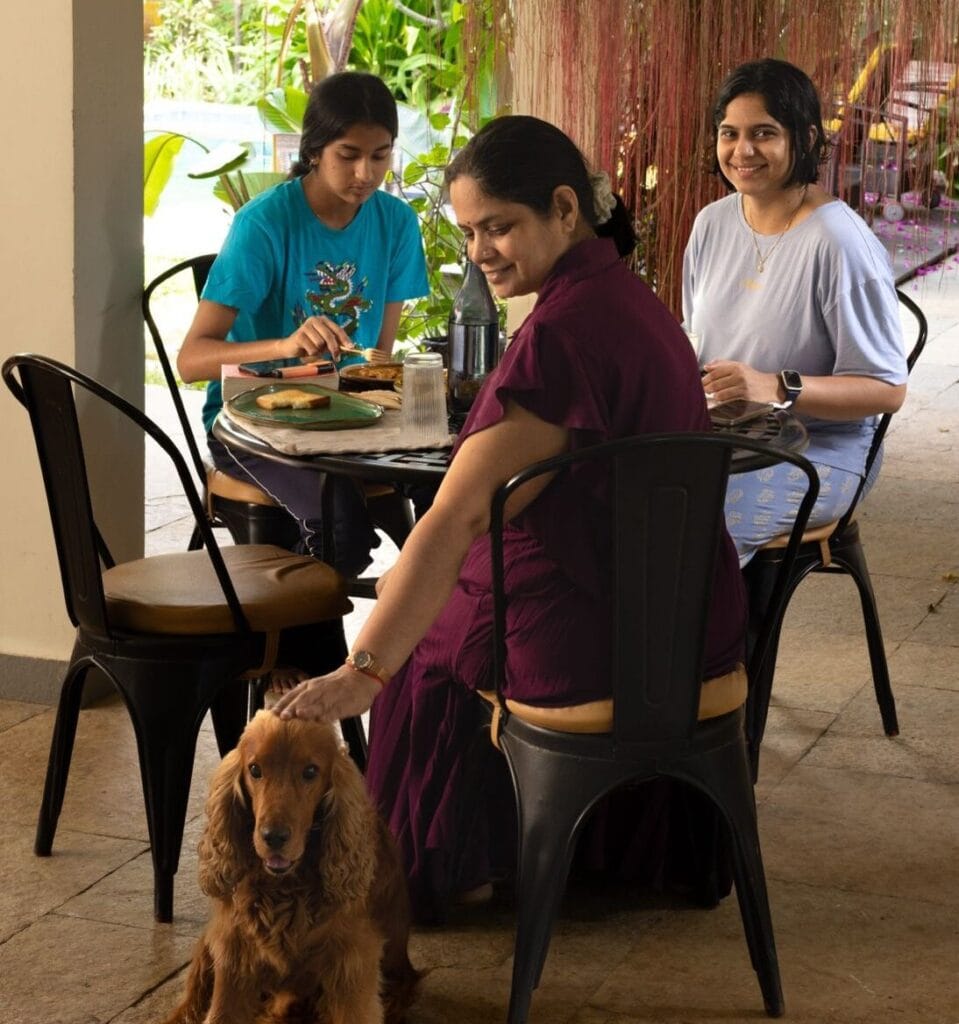 Guests enjoying breakfast with a pet dog at Orchid Tree Wellness Retreat